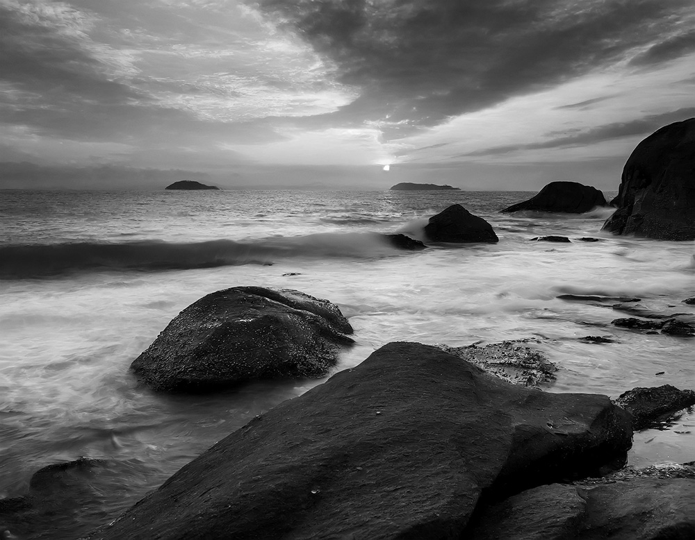 Sunset over ocean, large rocks in foreground